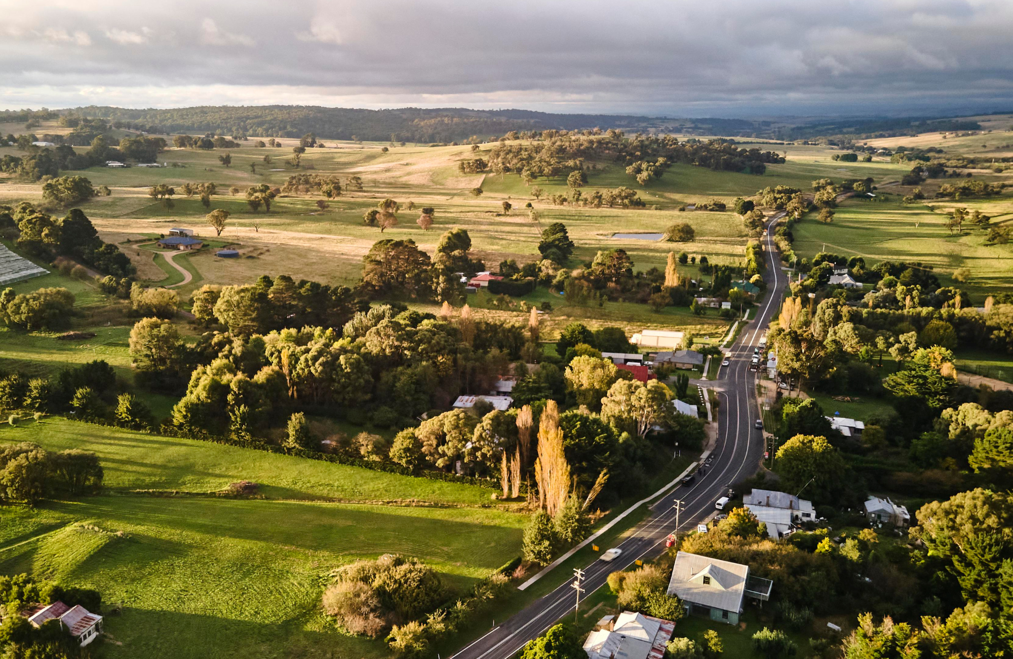 Aerial view of country road near Laggan in regional NSW depicting green paddock and a few buildings