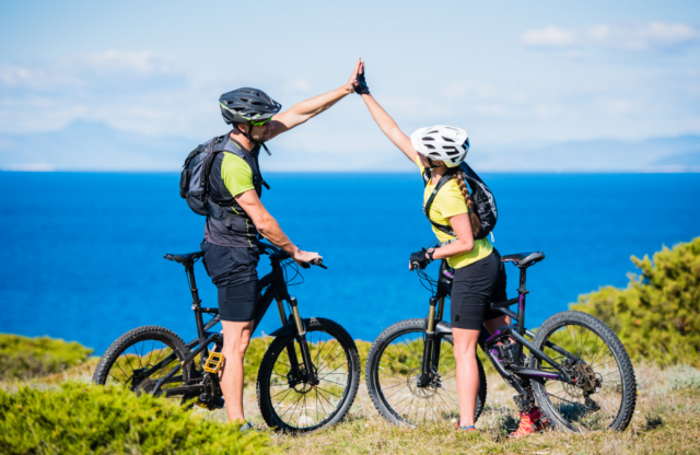 two people on mountain bikes giving each other a high five